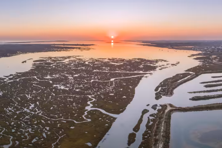 Pôr do sol sobre pântanos de maré, salinas e canais de lagoas.