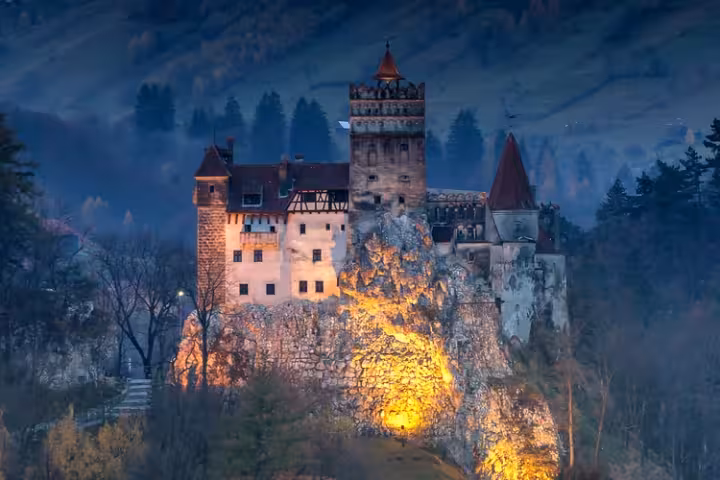 O Castelo de Bran iluminado ao entardecer sobre sua rocha, na Transilvânia.