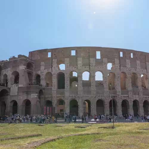 The outer walls of the Colosseum in Rome under a clear sky.