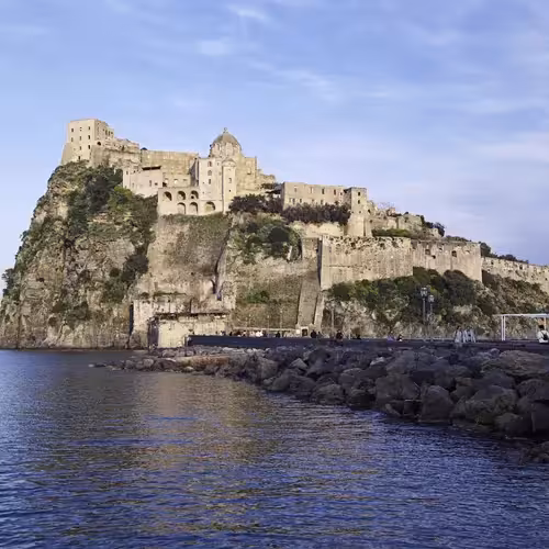 Des gens empruntent le pont menant au château aragonais, situé sur son îlot rocheux à Ischia.
