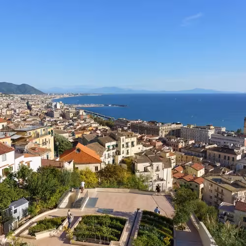 Des visiteurs sur une terrasse de jardin surplombant les toits de Salerne et son golfe