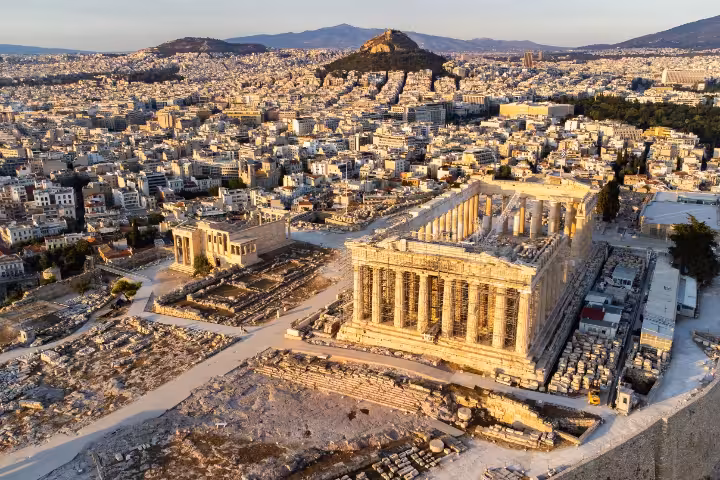 Aerial view of the Acropolis of Athens featuring the iconic Parthenon and Erechtheion surrounded by ancient ruins and the modern city skyline, perfect for planning a guided tour or self-guided visit to Greece's top historical landmark.