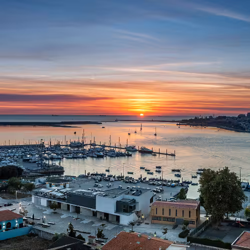 Vista del tramonto sul porto turistico di Afurada, nell'estuario del Douro, con barche e un cielo dai colori vivaci nella regione del Nord del Portogallo.