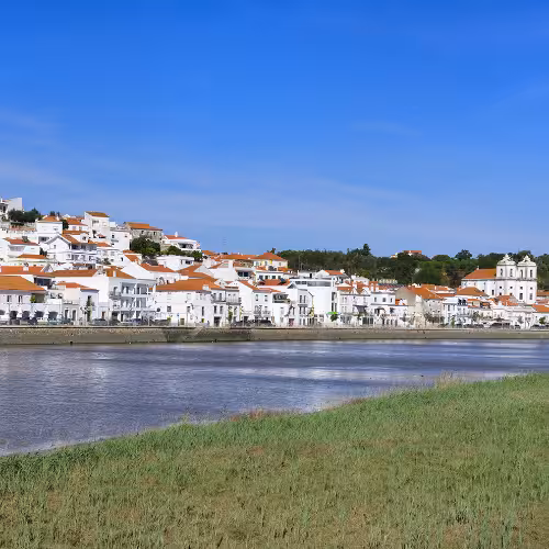 Veduta panoramica degli affascinanti edifici imbiancati a calce di Alcácer do Sal lungo il fiume Sado, nella regione dell'Alentejo, in Portogallo.