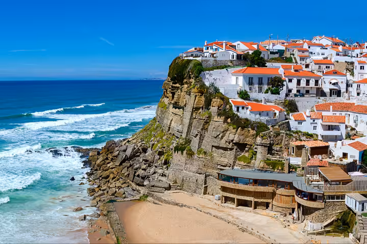 Breathtaking cliffside village of Azenhas do Mar in Sintra, Portugal, featuring traditional white houses with terracotta rooftops overlooking the stunning Atlantic Ocean waves, a must-visit destination for Portugal travel tours and holiday packages.