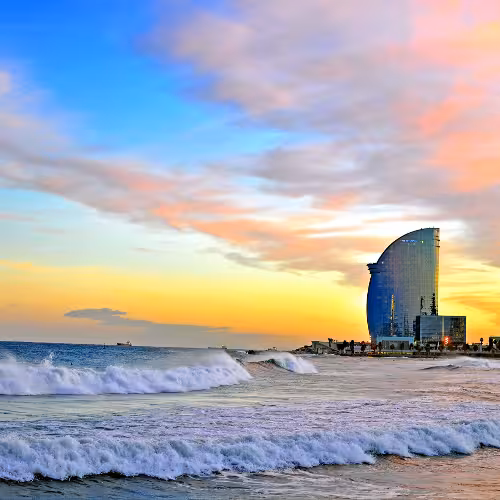 Vista do pôr do sol na Praia de Barceloneta e no hotel W Barcelona, na costa do Mediterrâneo, uma das principais atrações de Barcelona, Catalunha, para passeios à beira-mar e escapadelas urbanas na Espanha.
