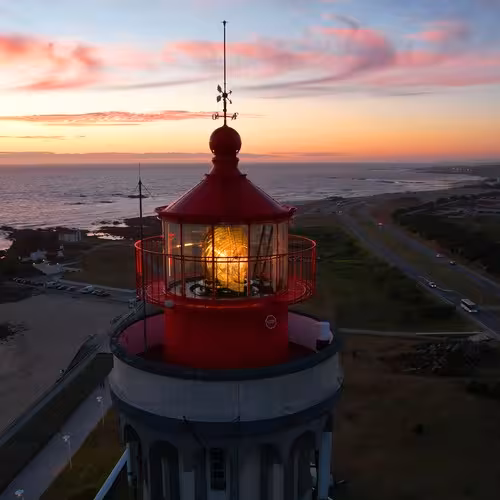 The red lantern of the Leça da Palmeira lighthouse at dusk, above the coast of Matosinhos, Portugal.