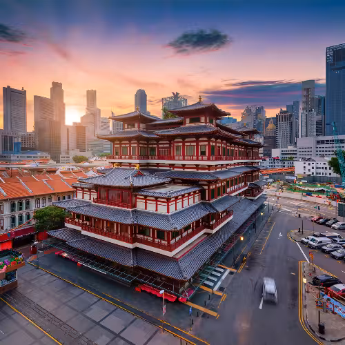Il Tempio della Reliquia del Dente di Buddha a Chinatown, Singapore, con lo skyline della città al tramonto sullo sfondo, mette in risalto il patrimonio culturale e l'esplorazione urbana.