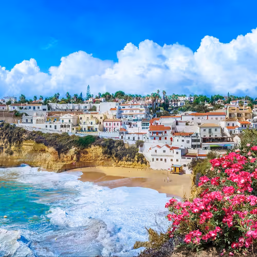 Scenic view of Carvoeiro coastline in the Algarve, Portugal, showcasing the vibrant cliffs, turquoise ocean, and charming whitewashed buildings.