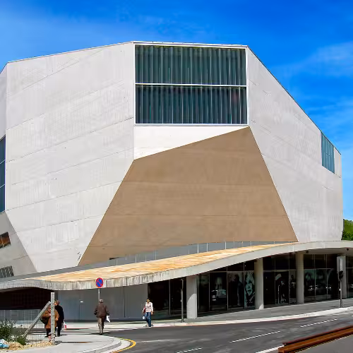 Arquitetura contemporânea da Casa da Música na Boavista, Região Norte, Portugal, apresentando o seu desenho geométrico único contra um céu azul claro.