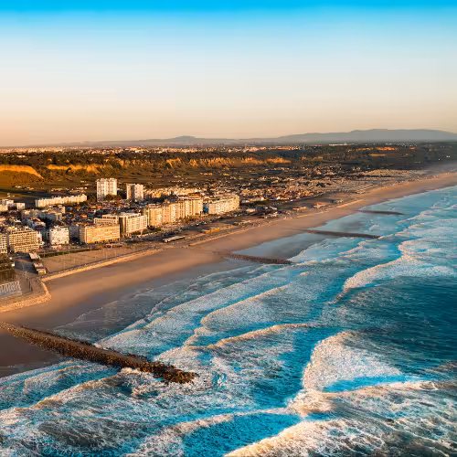 Vue aérienne de la plage de Costa da Caparica dans la région de Lisbonne, mettant en valeur son littoral magnifique et sa ville balnéaire animée.