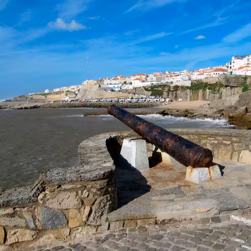 Vue panoramique des falaises côtières et de l'architecture historique d'Ericeira, mettant en valeur le charme de ce village balnéaire de la région de Lisbonne, au Portugal.
