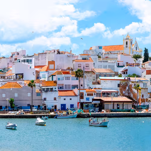 Scenic view of Ferragudo's colorful architecture along the waterfront in the Algarve region, Portugal, showcasing charming coastal village vibes.