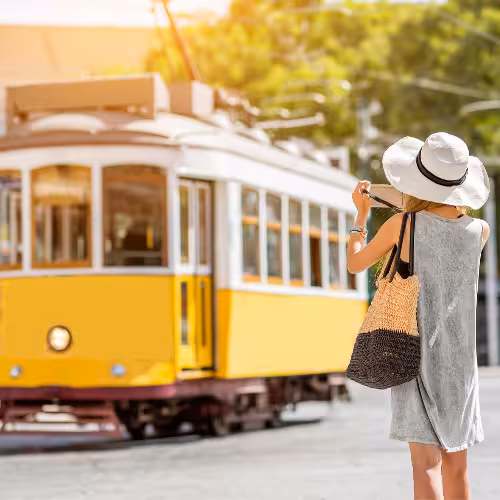 Un turista con un cappello da sole fotografa l'iconico tram giallo di Lisbona, in Portogallo, catturando l'essenza del viaggio e dell'esplorazione in questa vibrante città.