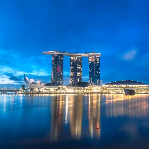 L'iconico skyline notturno del Marina Bay Sands di Singapore, con l'hotel, l'ArtScience Museum e le vivaci luci della città che si riflettono sulle acque di Marina Bay.