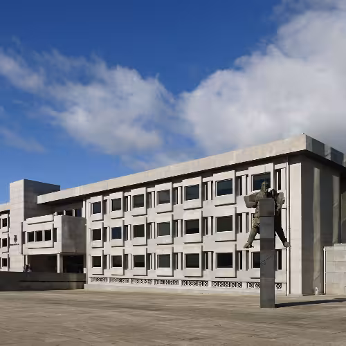 Edifício de arquitetura moderna com estátua na Cidade da Maia, apresentando marcos culturais da Região Norte de Portugal.