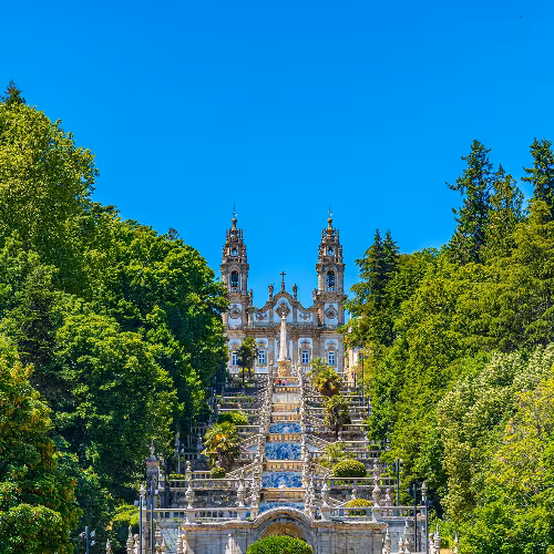 Sanctuaire Nossa Senhora dos Remédios à Lamego, Portugal, entouré d'une verdure luxuriante, mettant en valeur son architecture baroque emblématique et son grand escalier.