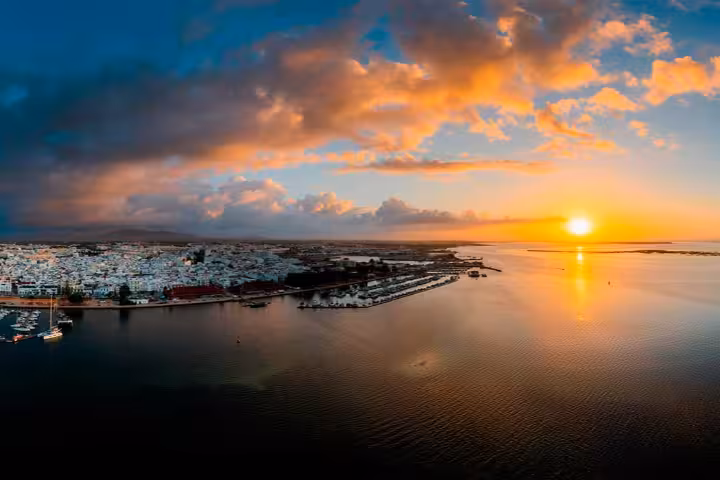 Breathtaking aerial panoramic view of Olhão waterfront marina at golden sunset with Ria Formosa lagoon, perfect for Tavira and Olhão boat tours and island-hopping adventures in the Algarve, Portugal.