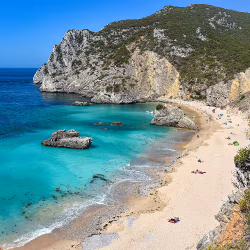 Águas azul-turquesa e falésias deslumbrantes na Praia da Ribeira do Cavalo, uma praia de visita obrigatória em Sesimbra, Região de Lisboa, Portugal.