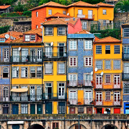 Fachadas coloridas de edifícios tradicionais da Ribeira ao longo do Rio Douro, na Região Norte, Portugal, apresentando arquitetura vibrante e charme cultural.