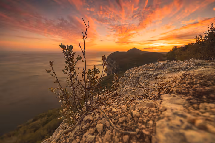 Breathtaking golden sunset view over Sesimbra's rugged coastal cliffs and Atlantic Ocean, perfect for private boat tours and scenic coastal experiences in Portugal.