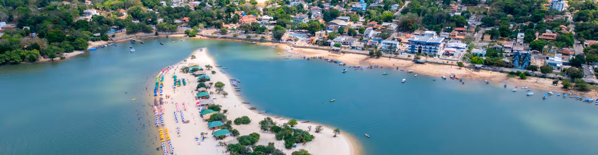 Aerial view of a sandy river beach with colorful umbrellas and small boats on the Amazon River in the State of Pará, Brazil, a popular eco-tourism and waterfront getaway.