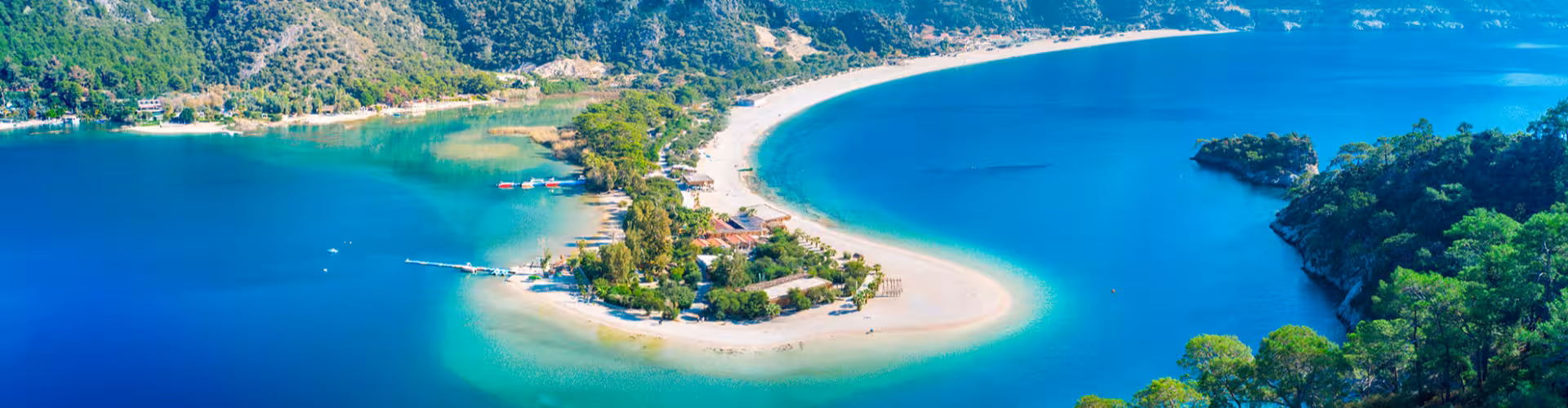 Aerial view of the stunning Blue Lagoon in Ölüdeniz, Muğla Province, showcasing pristine turquoise waters and lush greenery, a top travel destination in Turkey.