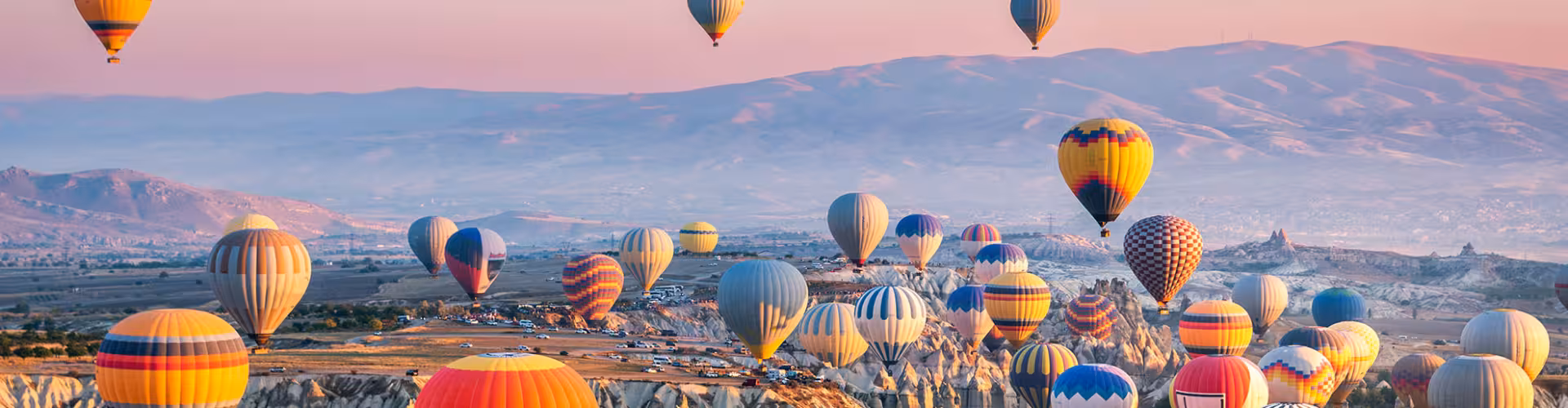 Colorful hot air balloons soar over the stunning landscapes of Cappadocia at sunrise in Nevşehir Province, Turkey.