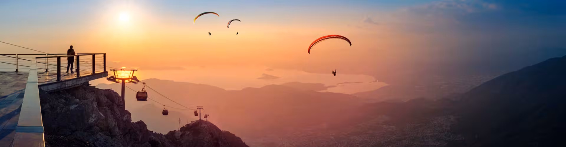 Paragliders soaring over a stunning sunset view from Babadağ Mountain in Fethiye, Turkey, with panoramic vistas of the Aegean coastline.