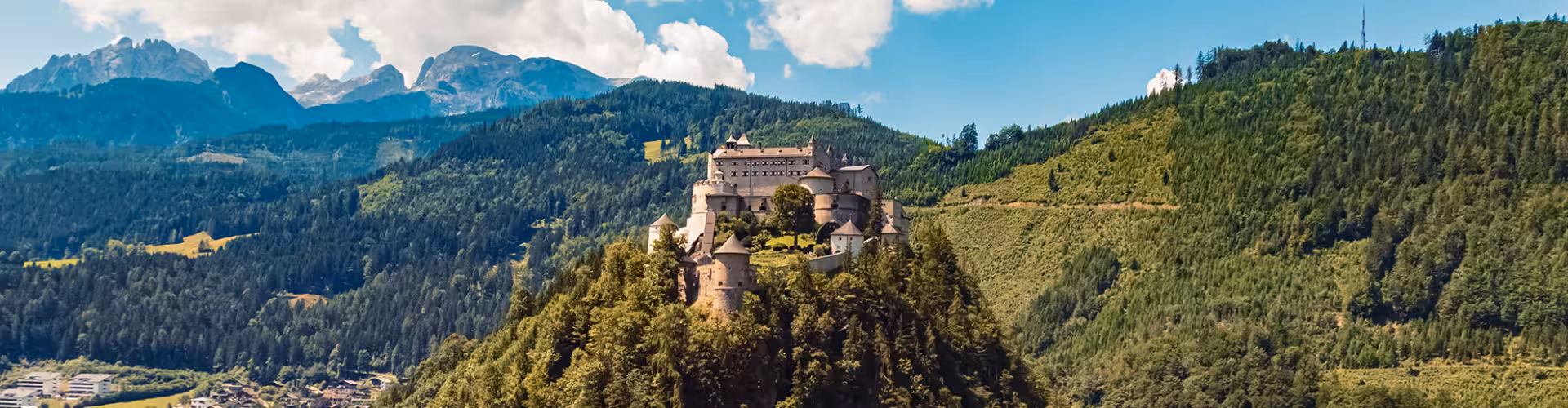 Hohenwerfen Castle overlooking the Salzach Valley in Werfen, Austria, with panoramic Salzburg Alps mountain scenery and lush forested hills