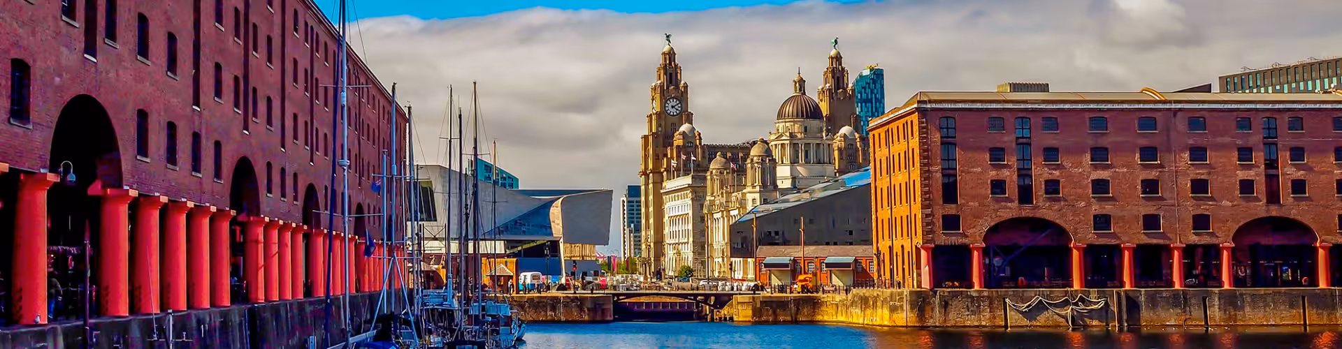Historic waterfront view of Liverpool featuring the iconic Royal Liver Building and Albert Dock under a vibrant sky.