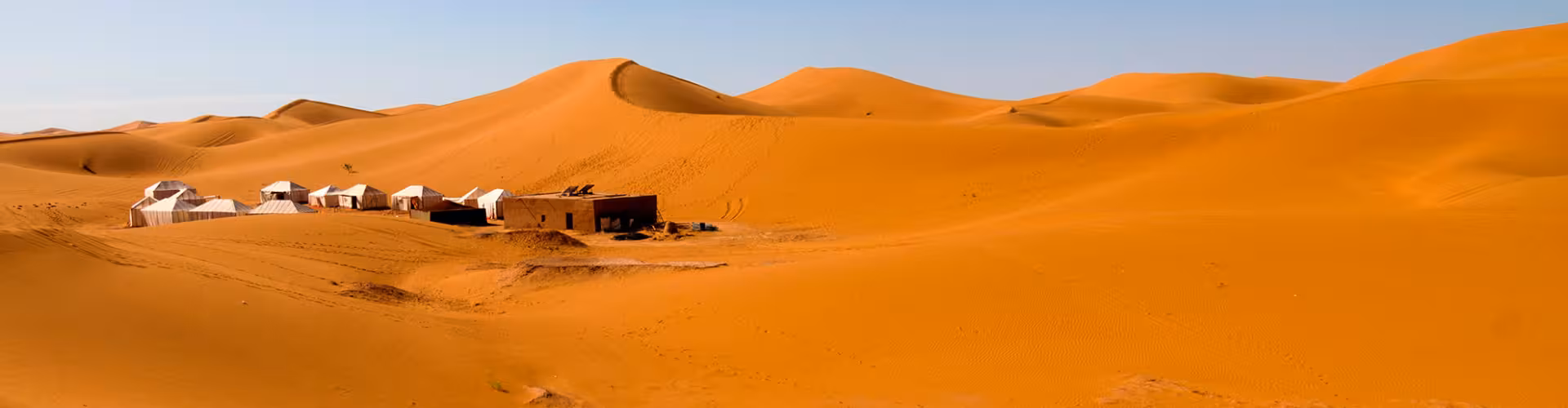 Luxury desert camp with traditional tents on the golden Erg Chigaga dunes near M'Hamid El Ghizlane, Morocco Sahara for camel trekking and sunset tours