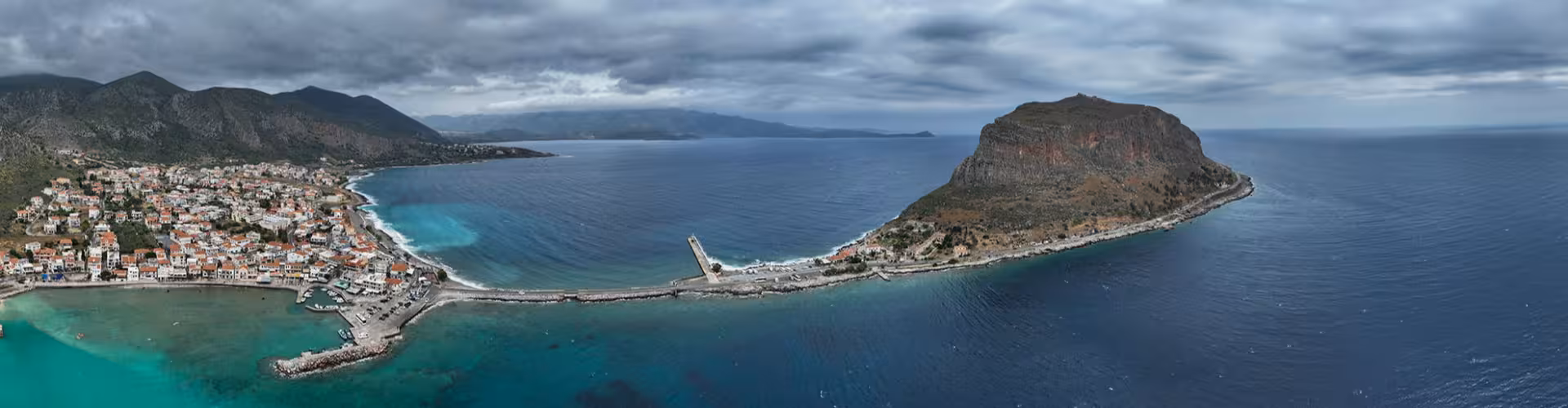 Aerial panorama of Monemvasia castle rock and seaside town on the Laconia coast, Peloponnese Greece, with turquoise waters and dramatic cliffs.