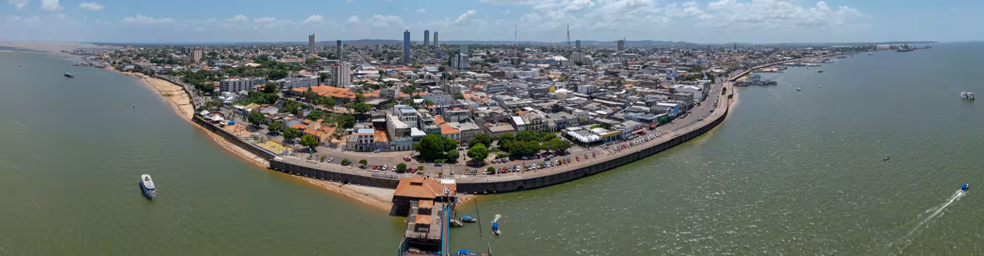 Aerial panoramic view of Santarém, Pará (PA), Brazil, showing the waterfront city skyline along the Amazon River with boats and the riverside promenade.
