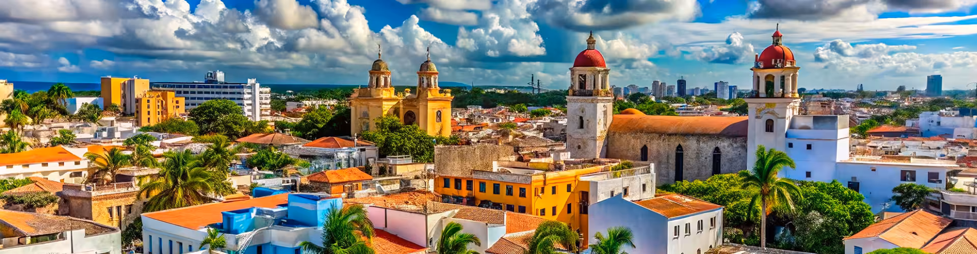 Colorful colonial skyline of Santo Domingo’s National District, Dominican Republic, featuring historic churches, red-domed towers, and the Zona Colonial cityscape under dramatic Caribbean skies