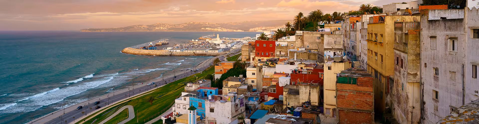 Panoramic sunset view of Tangier, Morocco, overlooking the Medina rooftops, Corniche seafront and the Strait of Gibraltar near the Port of Tangier.