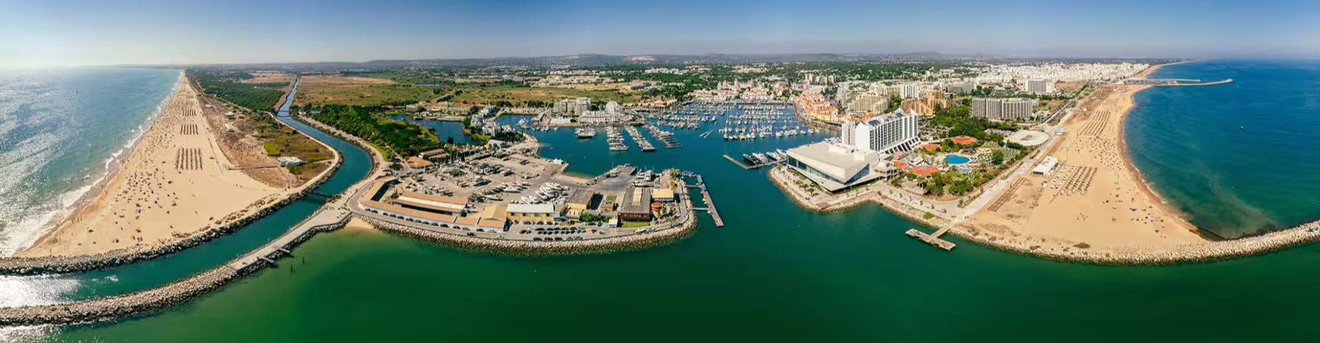 Aerial view of Vilamoura Marina showcasing luxury yachts, golden beaches, and vibrant holiday resorts in Algarve, Portugal.