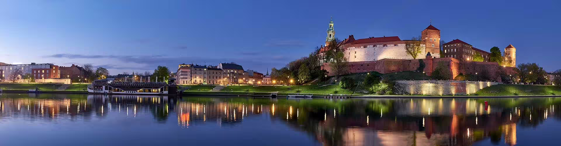 Wawel Castle and Vistula River at dusk in Krakow, Poland, reflecting the city's historic architecture and serene waterfront.