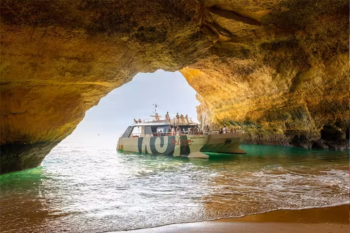 A sightseeing catamaran entering the famous Benagil sea cave on an Albufeira coastline boat tour in Portugal