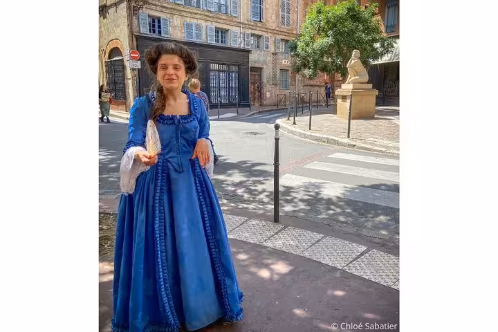 Guide in blue 18th century gown on a sunny street in Toulouse Saint-Étienne district