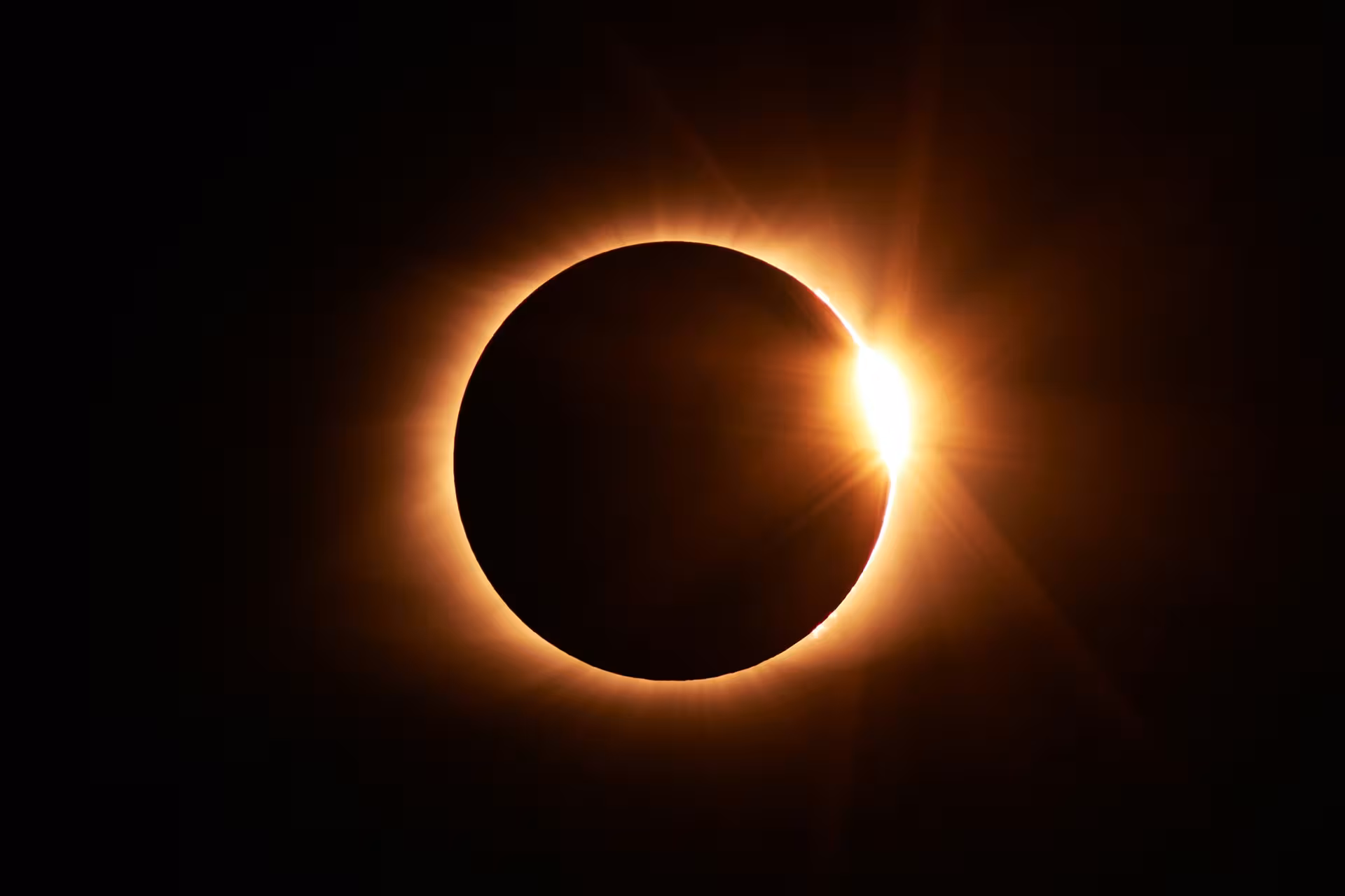Total solar eclipse diamond ring effect with glowing corona against dark sky