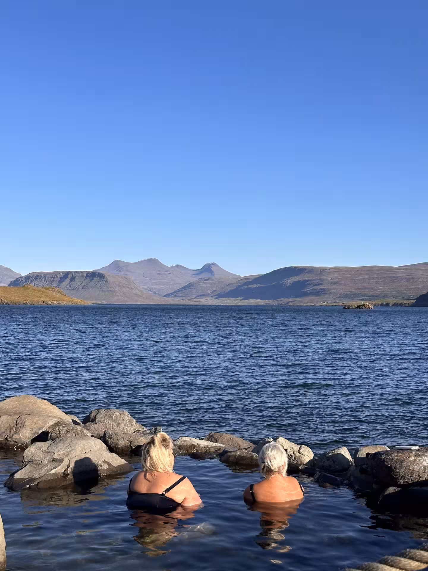 Relaxing in natural hot springs with scenic mountain views during the 2026 Total Solar Eclipse Tour experience.