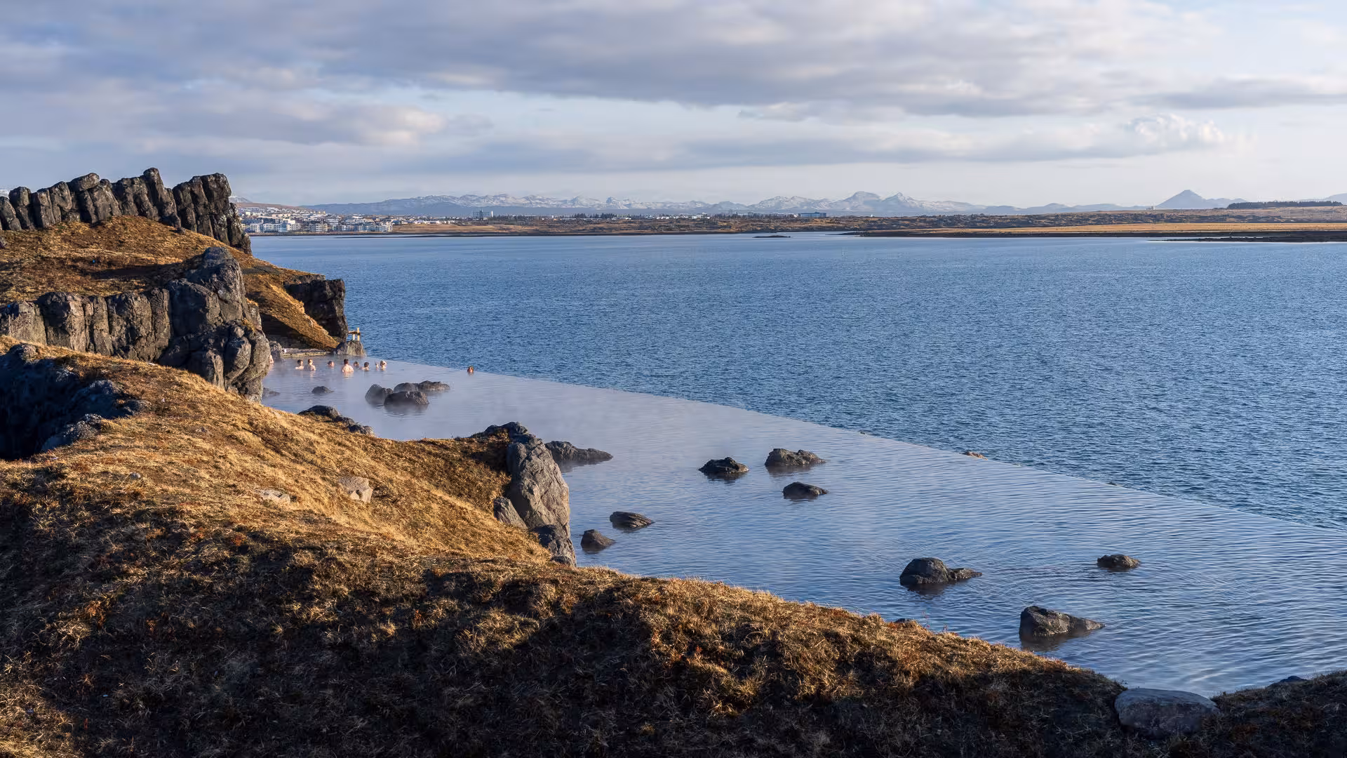 Visitors relax in a geothermal pool overlooking Icelandic landscapes on the 2026 Total Solar Eclipse Tour.