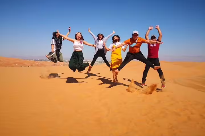 Group enjoying a jump in the golden sands of Oman's desert, part of a thrilling 3-day private tour experience.