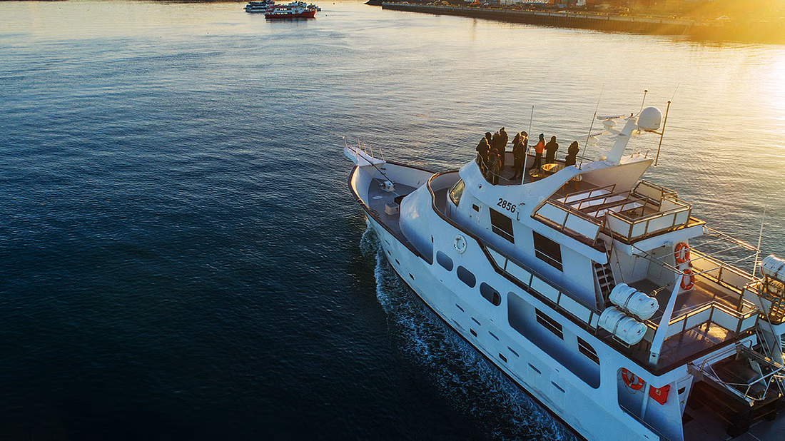 An aerial shot of a yacht with people onboard the deck