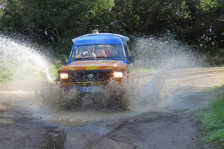 4x4 adventure vehicle splashing through water on a rugged trail during the Guided Tour Beyond Vineyards Cabo Girão Skywalk.