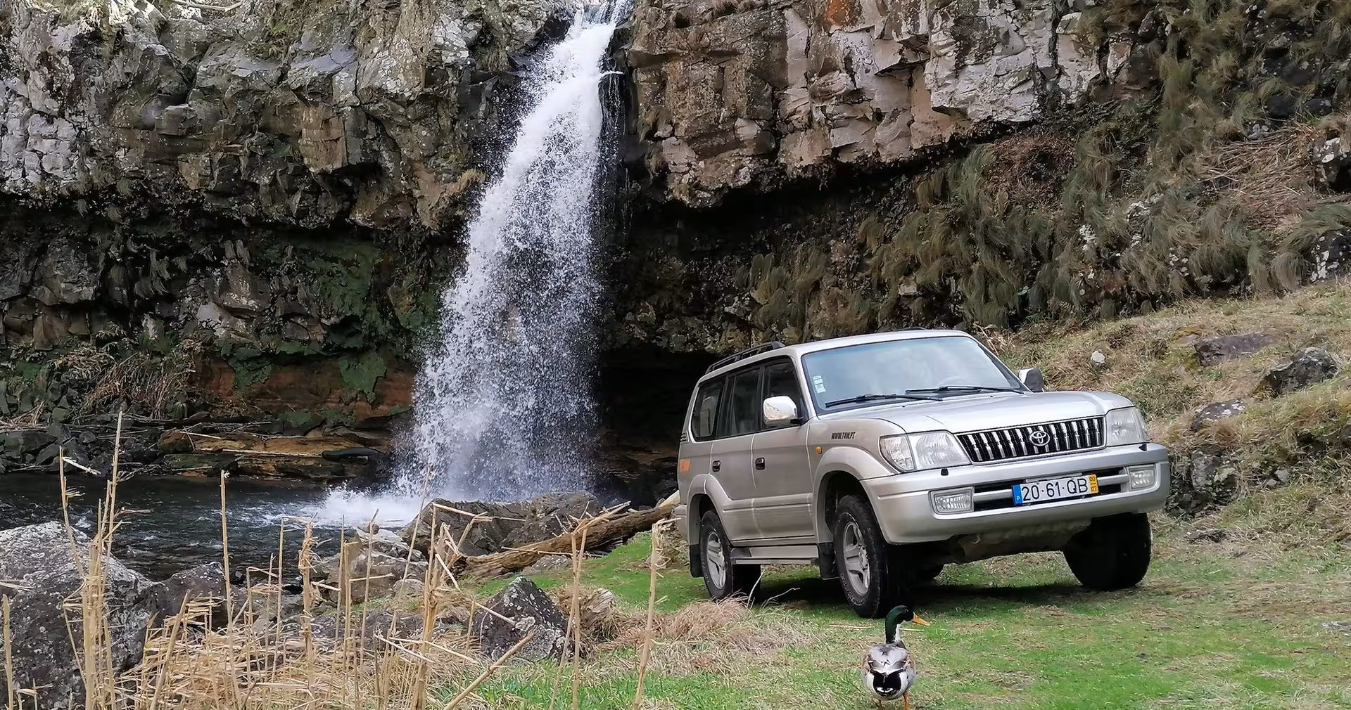 4x4 jeep parked beside remote Azores waterfall and lush cliffs on an off road half day private tour from Ponta Delgada