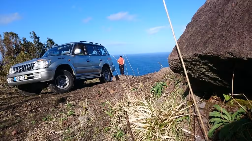 Off-road 4x4 parked on a cliffside track overlooking the Atlantic Ocean during a full day private tour from Ponta Delgada