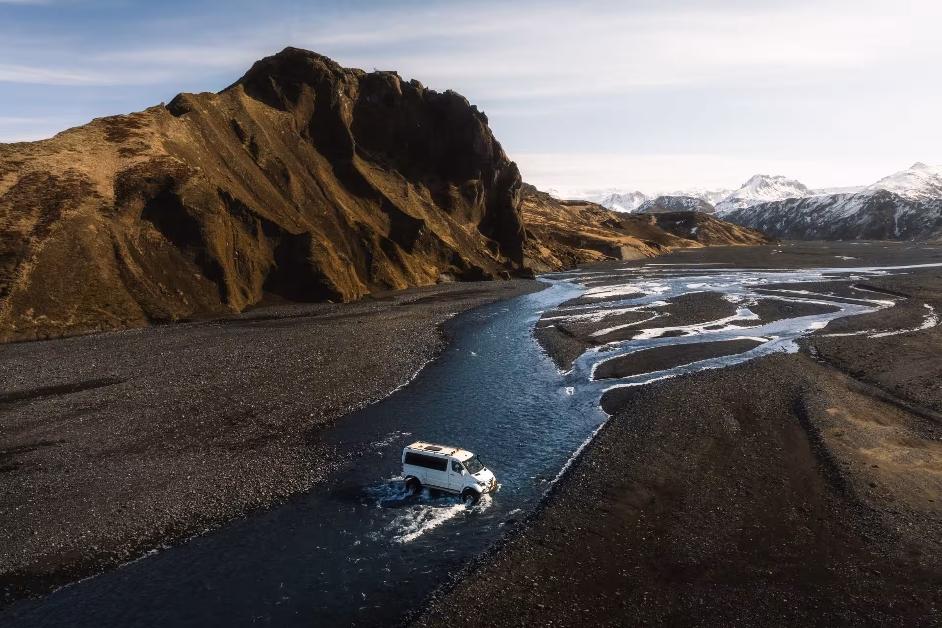 White 4x4 van crossing a glacial river in Thorsmork Iceland with dramatic mountains behind
