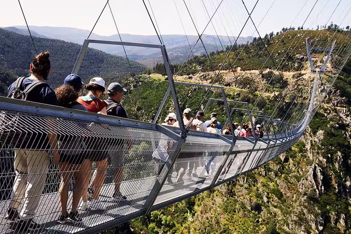 People crossing the impressive 516 Arouca Suspension Bridge, enjoying panoramic views of the surrounding lush landscapes.